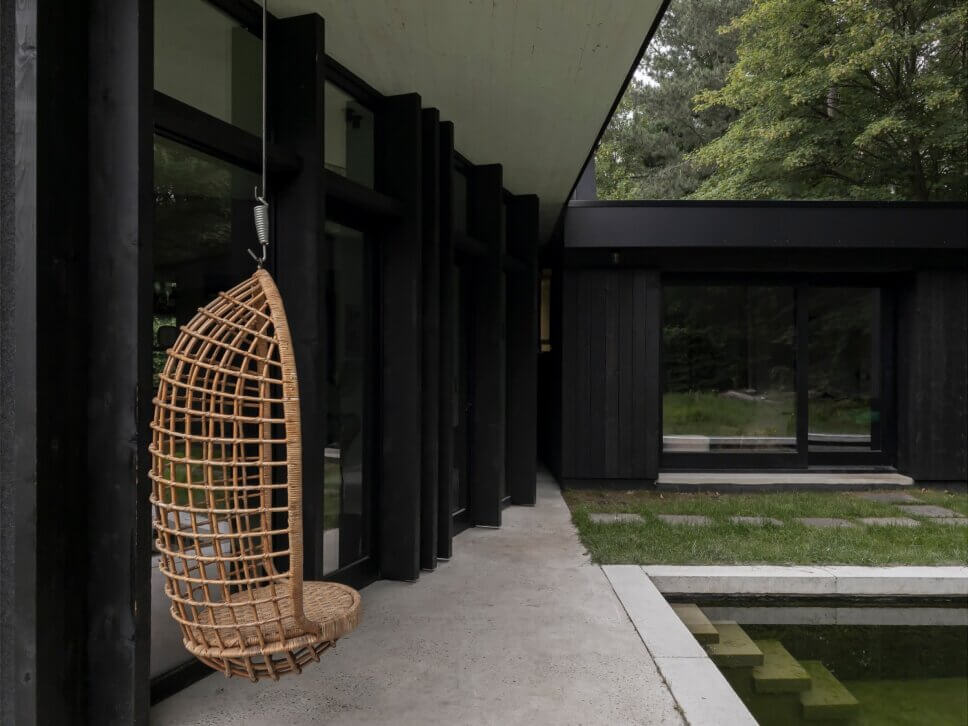 Mit schwarzem Holz verkleideter moderner Bungalow mit Pool im Garten