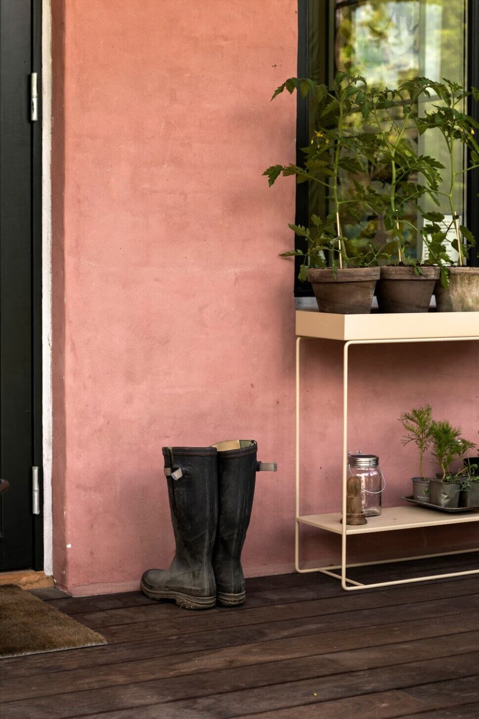 Behaglich mit Korbsofa und Esstisch eingerichtete Veranda einer alten Villa mit großem Garten. Eine Vase mit üppigem Blumenstrauß steht auf dem Tisch