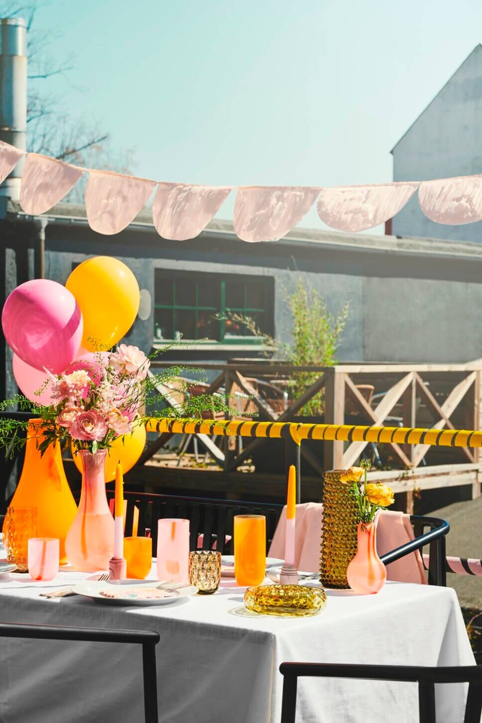 Farbenfroh in Rosa und Orange gedeckter Tisch auf Balkon