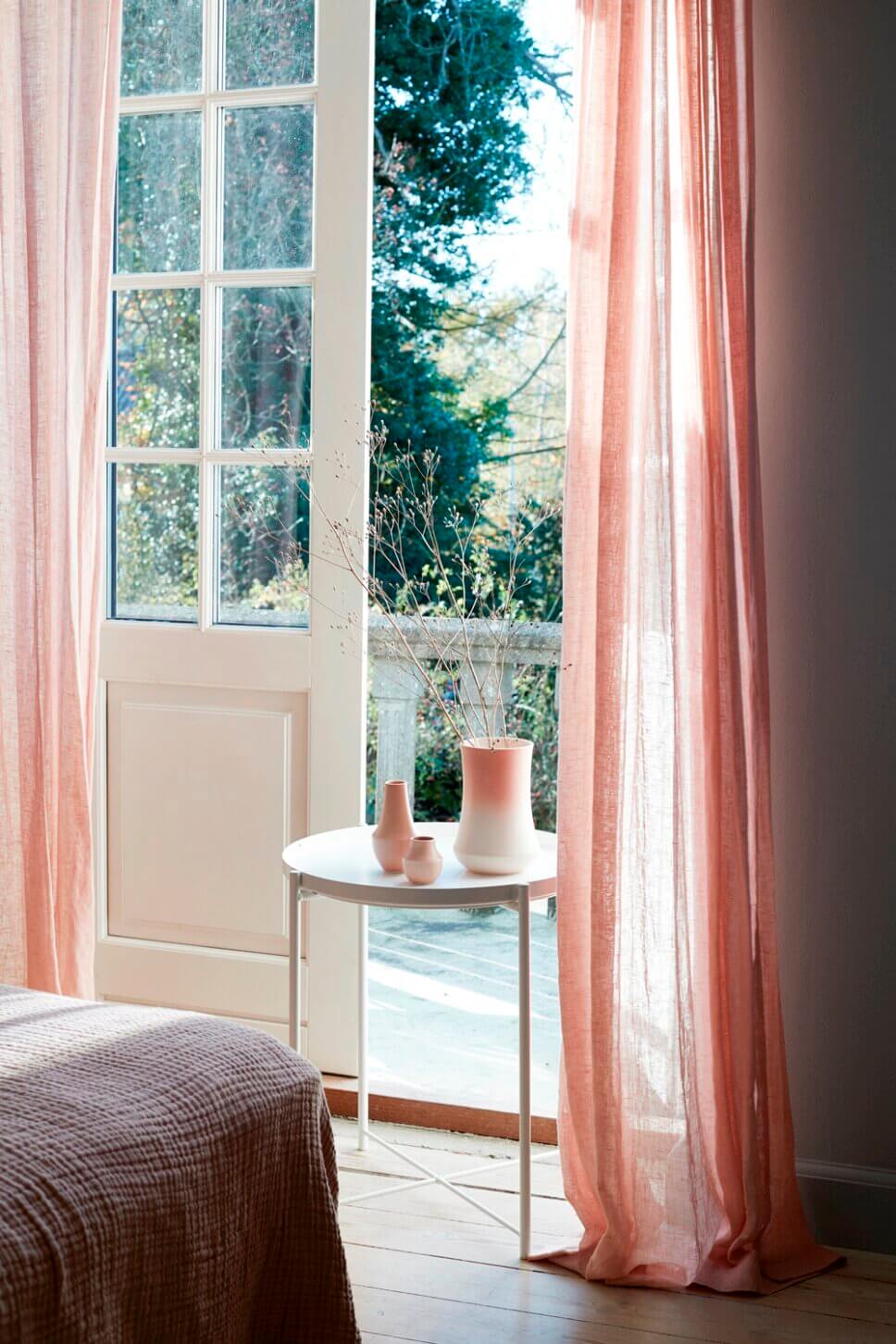 Modern eingerichtetes Schalfzimmer mit Rosa VAse vor offener Terrassentür