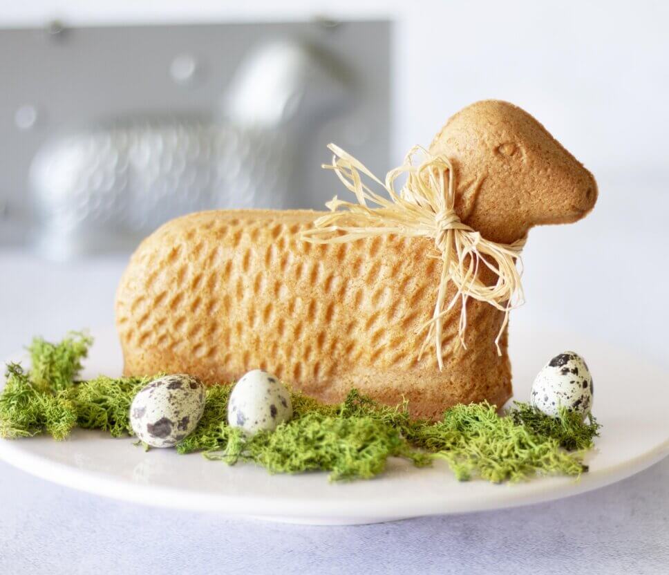 Osterlamm als Kuchen auf festlich gedeckter und mit Osterdeko geschmücktem Tisch