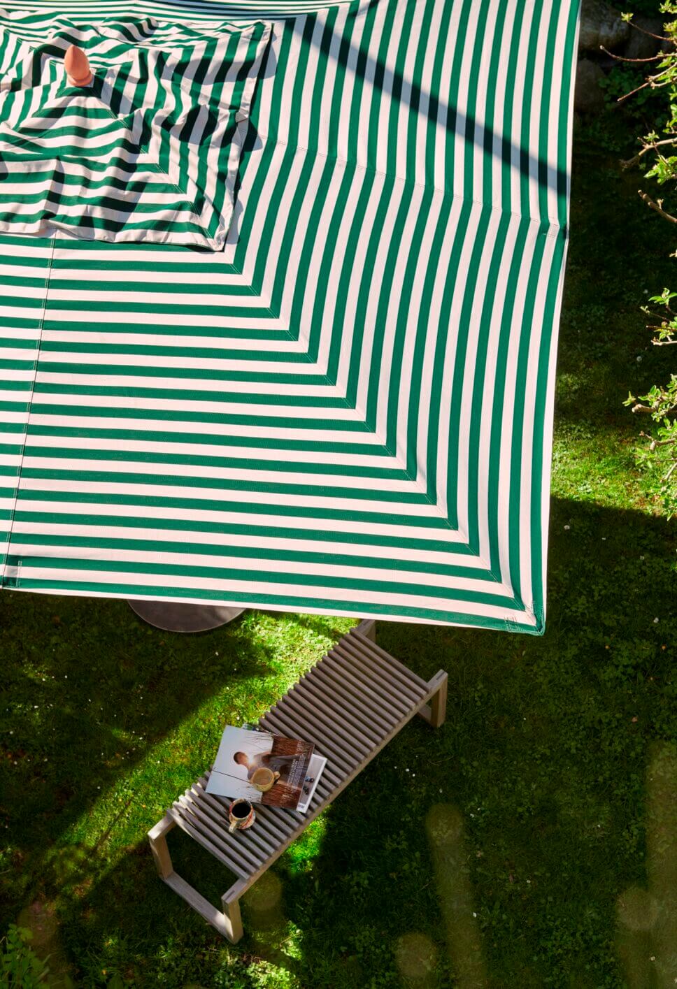 Moderne Gartenbank im Garten unter Sonnenschirm