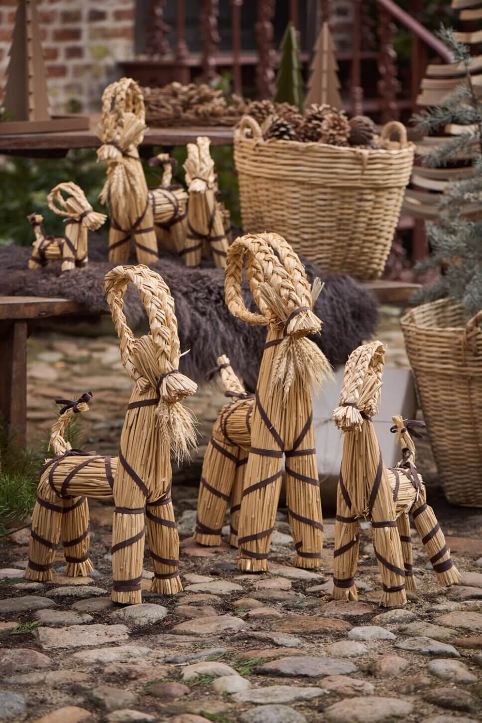 Julböcke aus Stroh stehen auf Kopfsteinpflaster im Hof