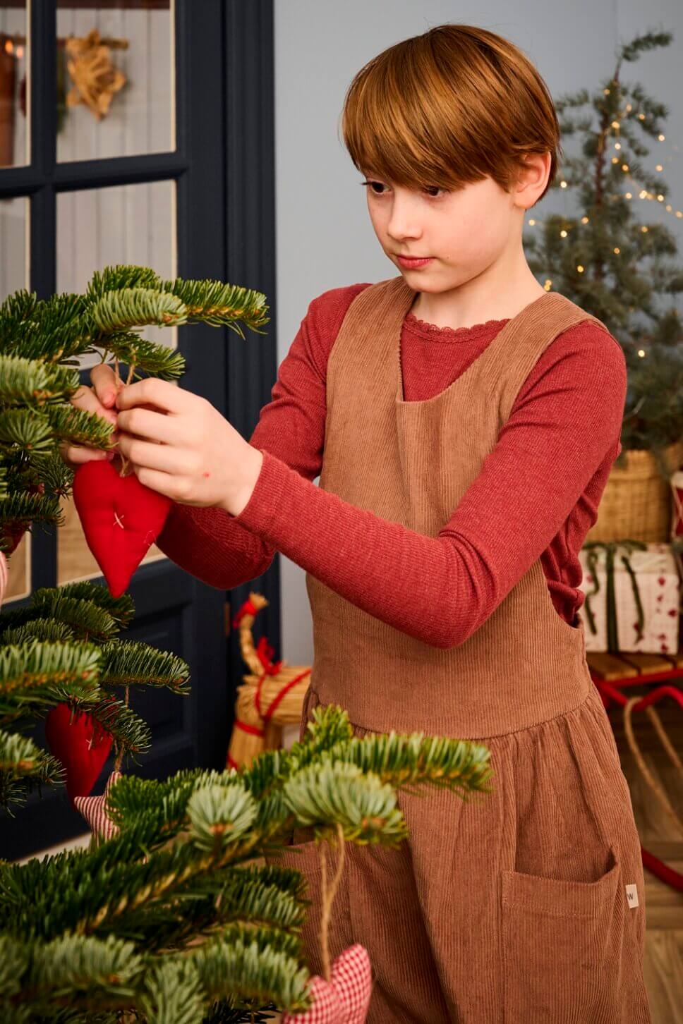 Mädchen schmückt Weihnachtsbaum im Wohnzimmer im Altbau