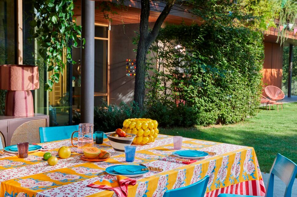 Behaglich mit farbenfrohen Stoffen und Designklassikern modern eingerichtete Terrasse mit liebevoll gedecktem Tisch an italienischem Bungalow
