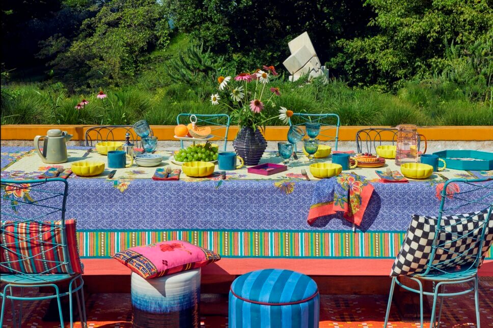 Behaglich mit farbenfrohen Stoffen und Designklassikern modern eingerichtete Terrasse mit liebevoll gedecktem Tisch an italienischem Bungalow