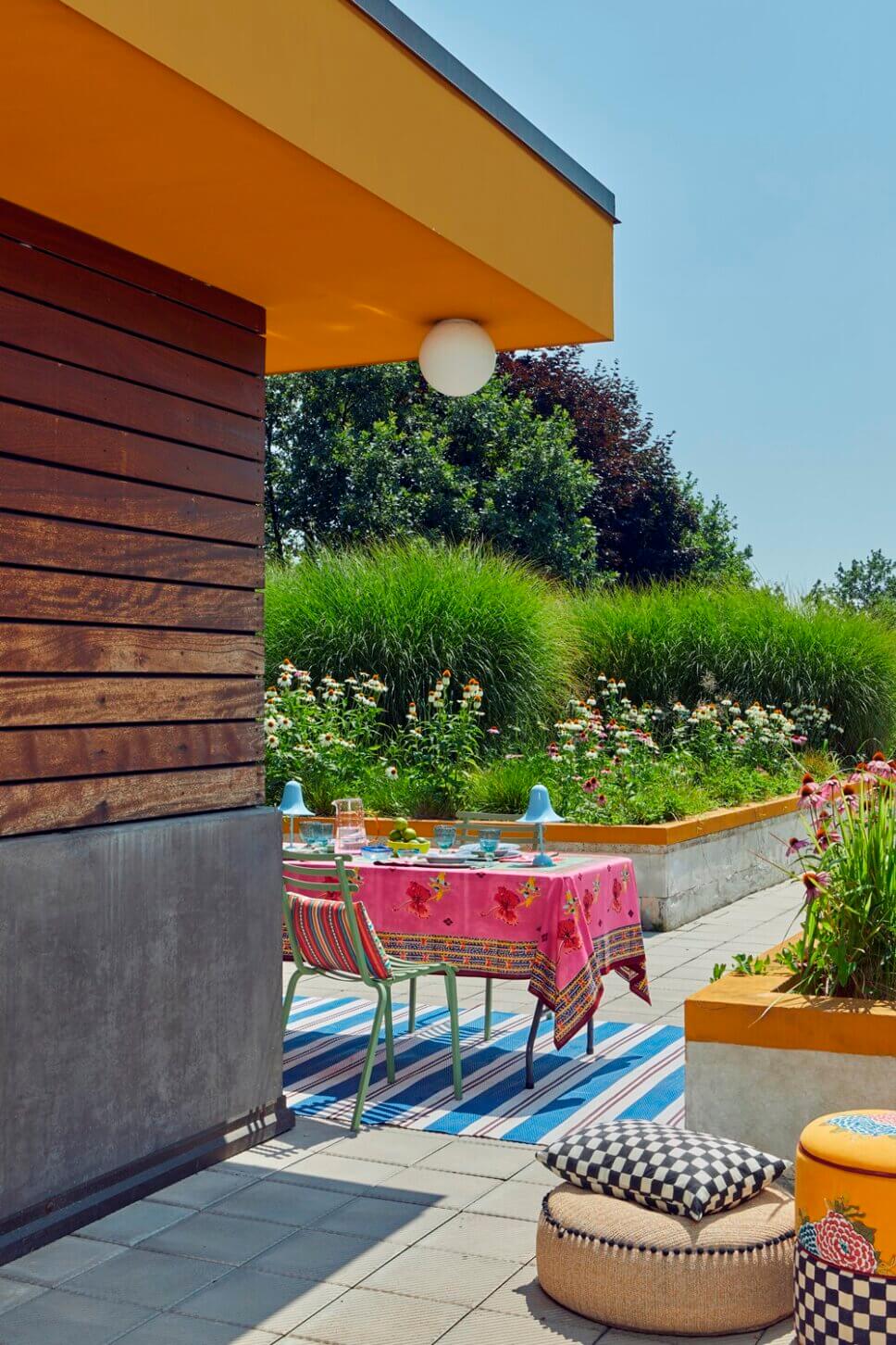 Behaglich mit farbenfrohen Stoffen und Designklassikern modern eingerichtete Terrasse mit liebevoll gedecktem Tisch an italienischem Bungalow