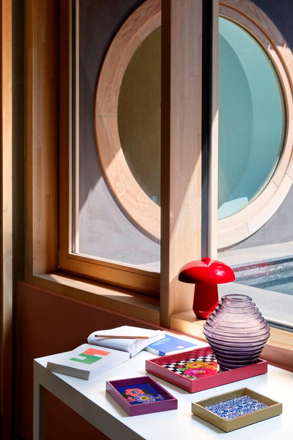 Behaglich mit farbenfrohen Tabletts und Designklassikern modern eingerichtetes Wohnzimmer in italienischem Bungalow