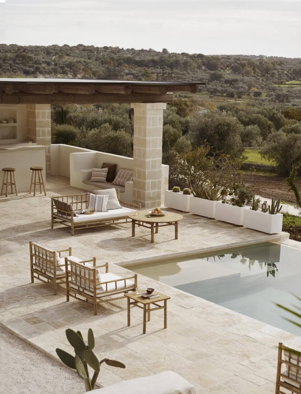 Bambus-Gartenliegen auf der Terrasse neben einem Pool in mediterraner Landschaft