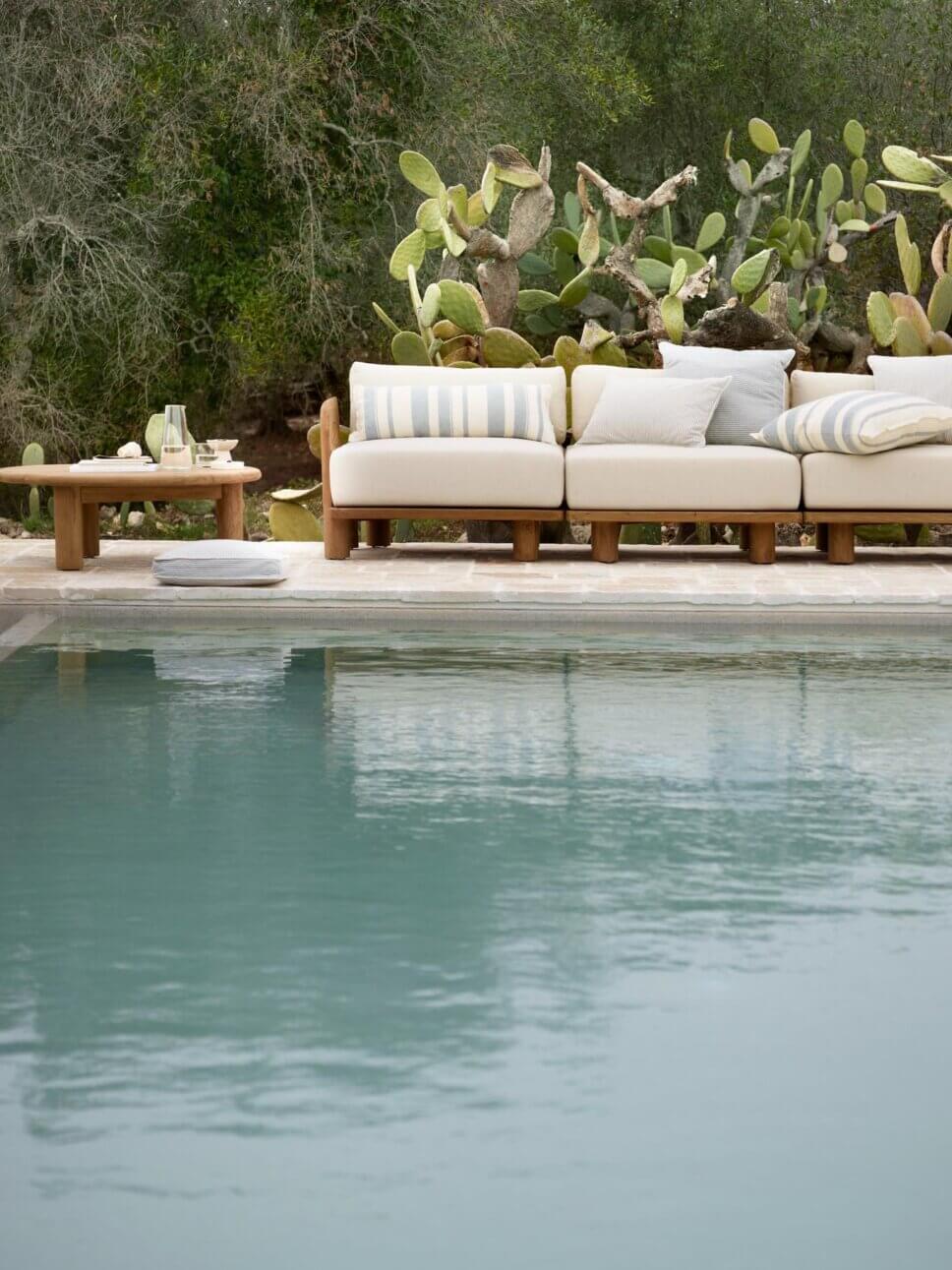 Holz-Gartenmöbel auf der Terrasse vor Pool in mediterraner Landschaft