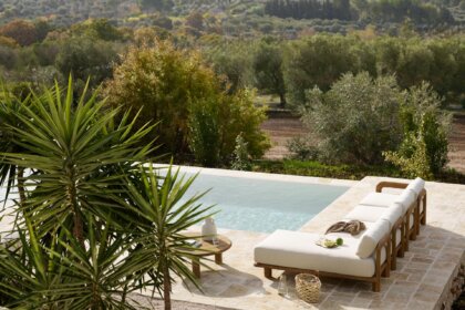Holz-Gartenmöbel auf der Terrasse vor Pool in mediterraner Landschaft