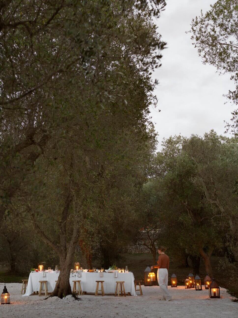 Gedeckte lange Tafel in mediterranen Garten beleuchtet von vielen Laternen