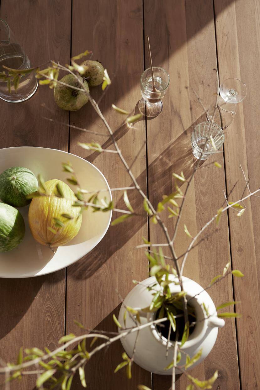 Blumenvase, Obstschale und Gläser auf Holztisch