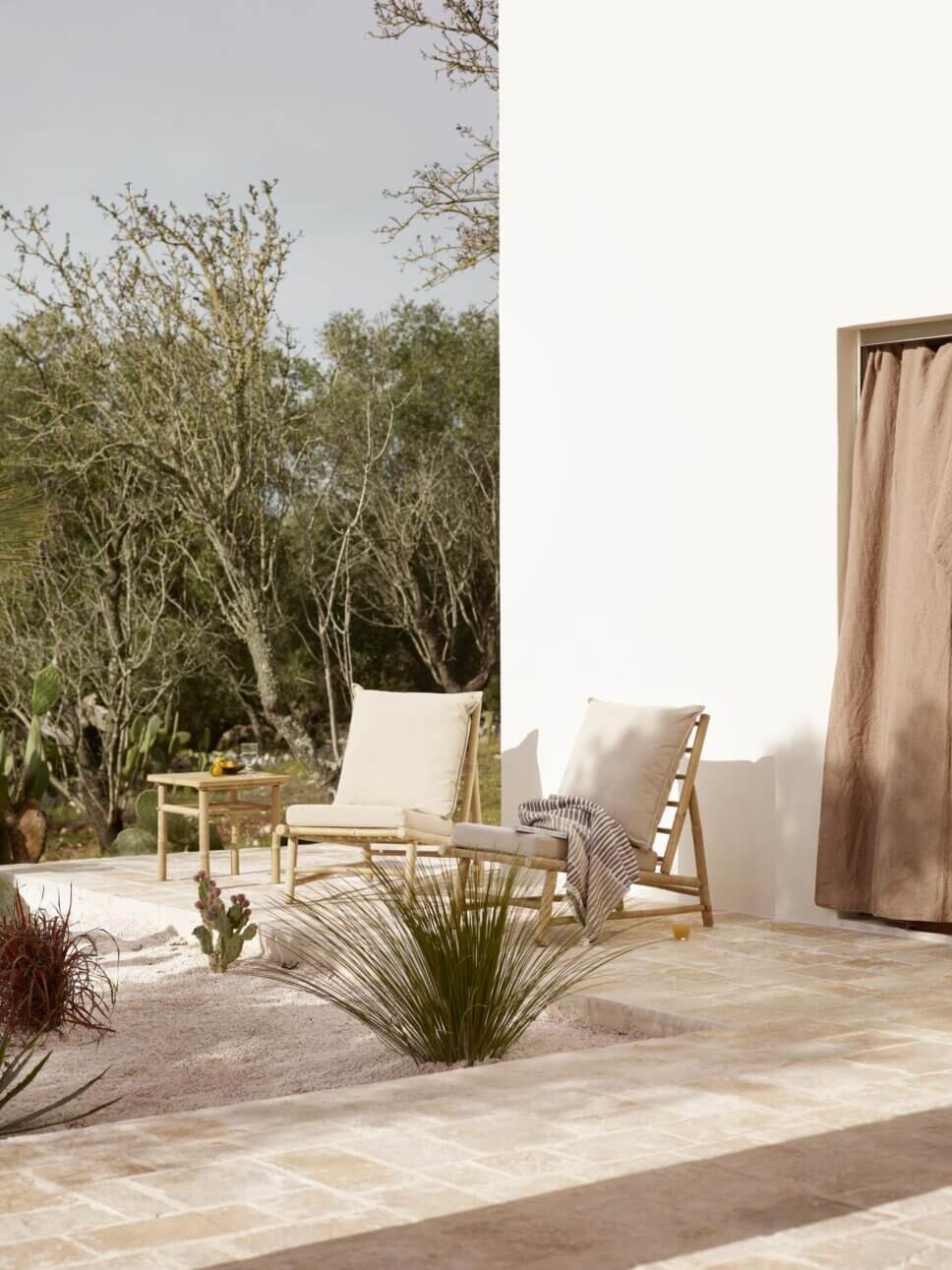 Mediterranes weißes Haus mit Bambus-Gartenmöbeln auf der Terrasse