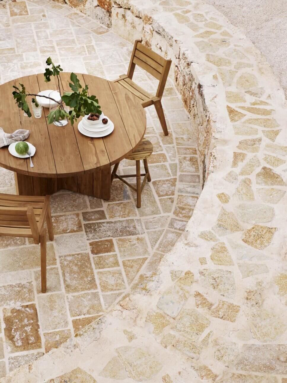 Holz-Gartenmöbel auf Terrasse aus Natursteinen