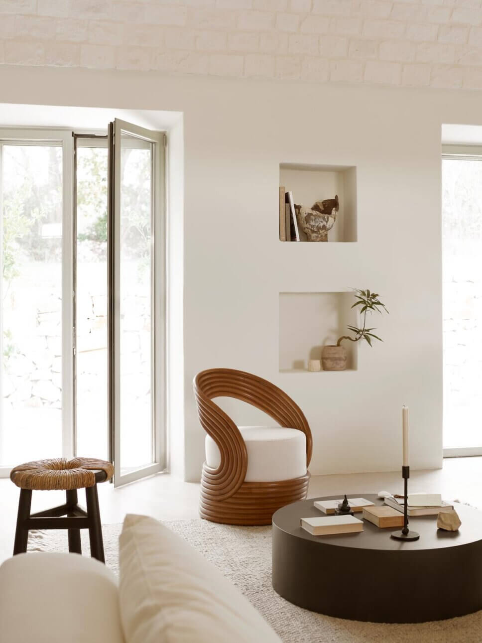 Modernes Wohnzimmer mit weißem Sofa und Rattanmöbeln in mediterranem Haus mit steinerner Gewölbedecke