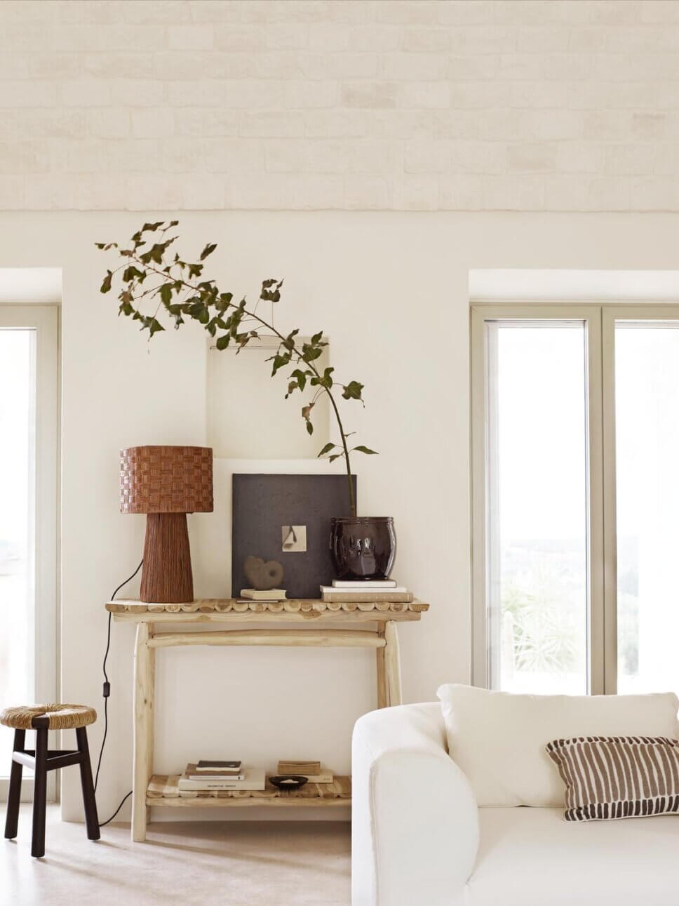 Modernes Wohnzimmer mit weißem Sofa und Rattanmöbeln in mediterranem Haus mit steinerner Gewölbedecke