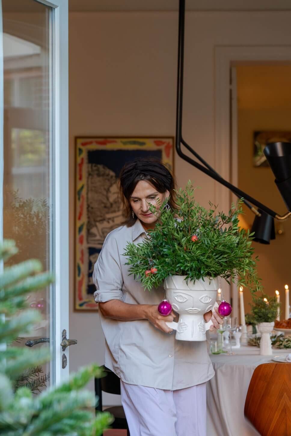Frau tr#gt festlich mit Weihnachtsdeko geschmückte Vase