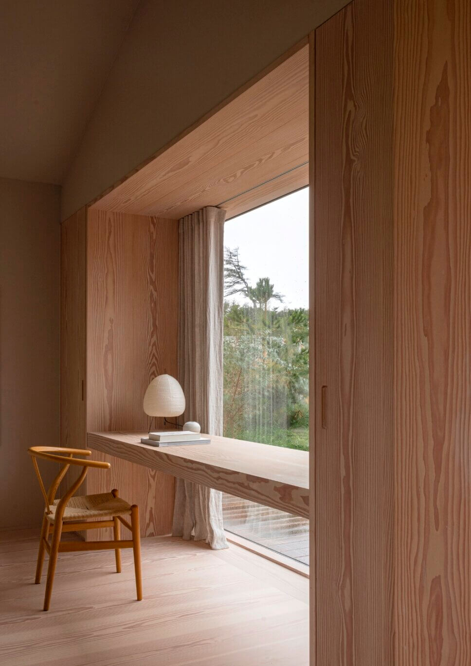 Minimalistisch eingerichtete, mit Holz vertäfeltes Zimmer mit Schreibtisch im großen Fenster in Architektenhaus