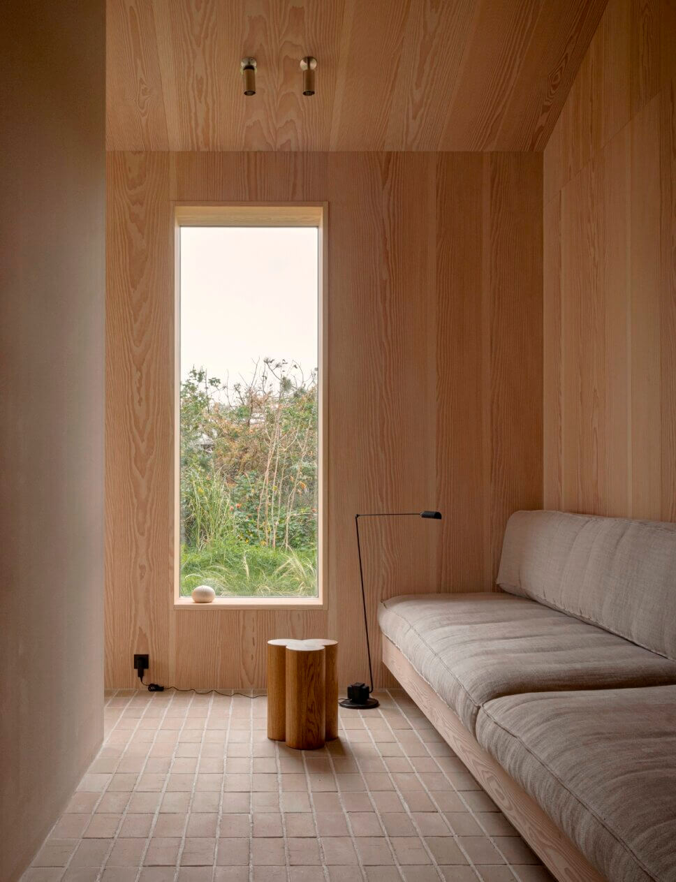 Minimalistisch eingerichtetes, mit Holz vertäfeltes Wohnzimmer in Architektenhaus mit raumhohem Fenster