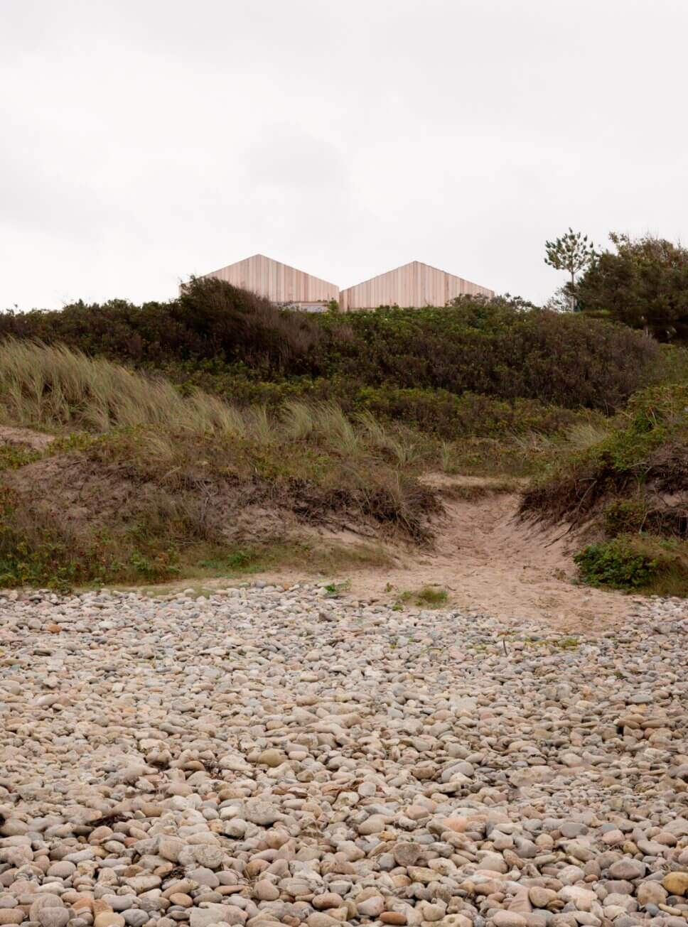 Blick vom Strand aus ein mit Holz verkleidetes Architektenhaus