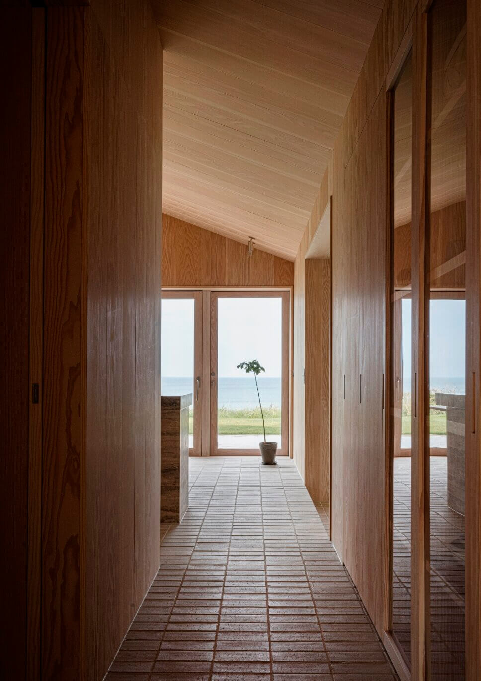 Blickachse im Flur in einem minimalistisch eingerichteten, mit Holz vertäfelten Architektenhaus