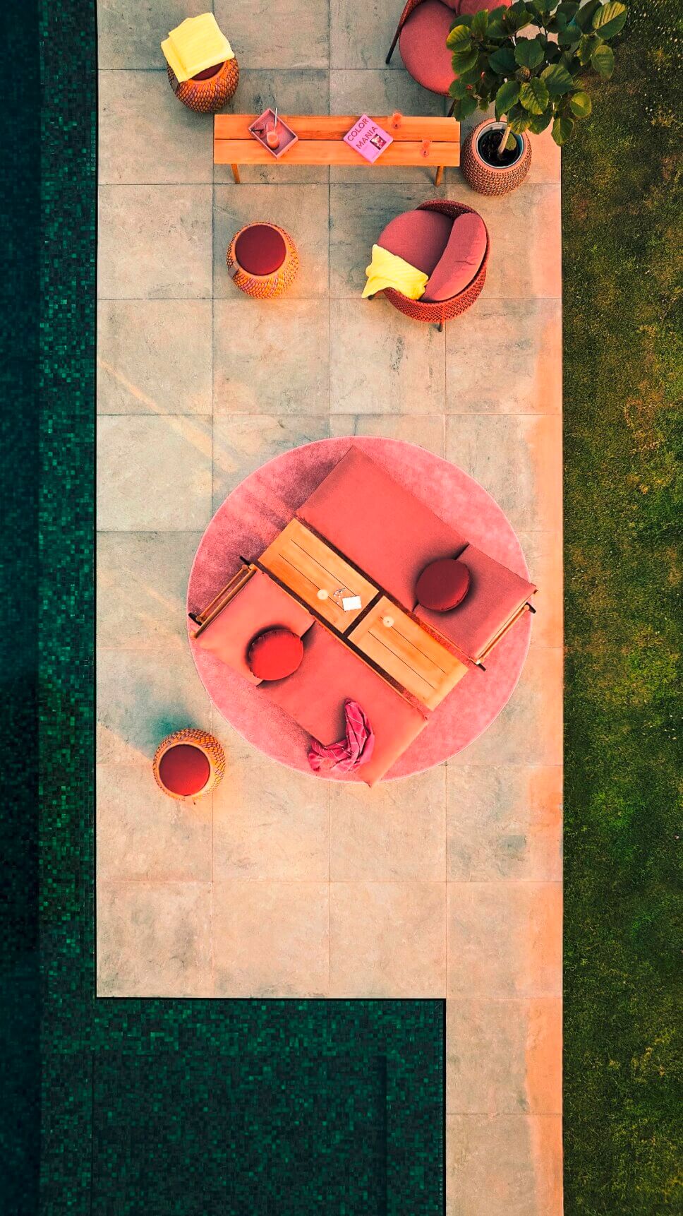 Gartenliegen mit roten Polstern auf der Terrasse neben einem Pool