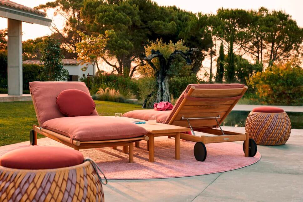 Gartenliegen mit roten Polstern auf der Terrasse neben einem Pool