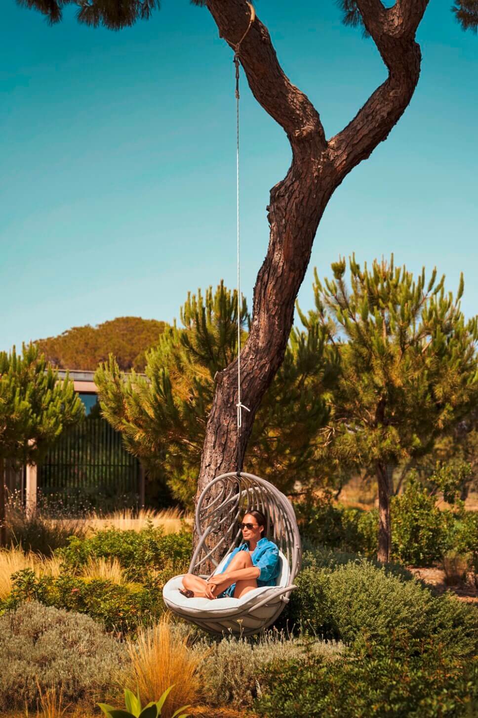 Gartenschaukel aus Geflecht im Baum hängend