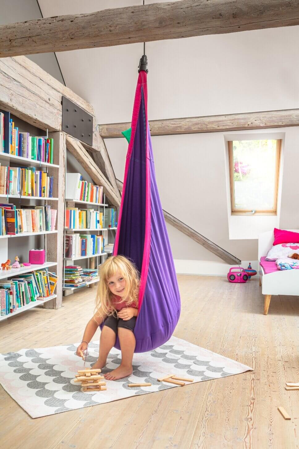 Kind schaukelt in modernem Hängesessel in Wohnzimmer